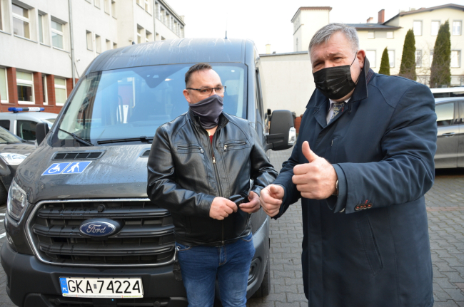 Burmistrz i Kierowca stoją przed samochodem. Przekazanie kluczyków.